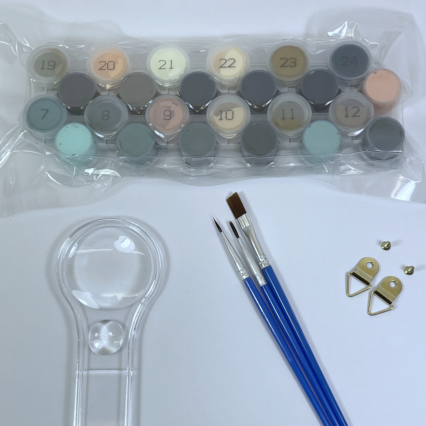 Set of paint pots, paintbrushes, and a magnifying glass on a white background.