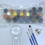 Set of acrylic paints in plastic, paint brushes and a magnifying glass on a white background.